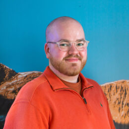 The headshot of a junior creative executive against the backdrop of a mountain range.