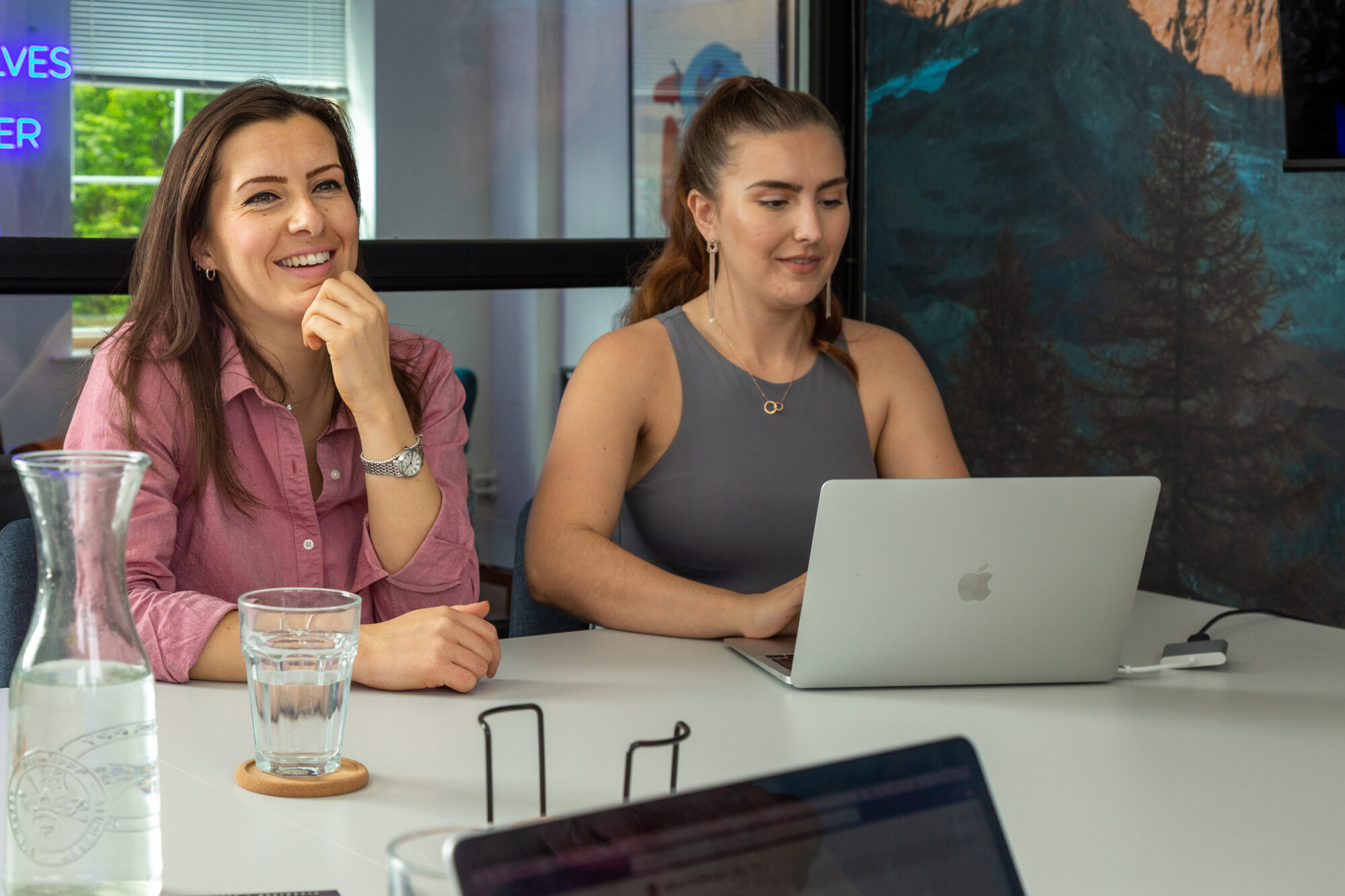 A senior content writer and head of digital communications from HB2B sitting in the boardroom at the table discussing marketing strategies.