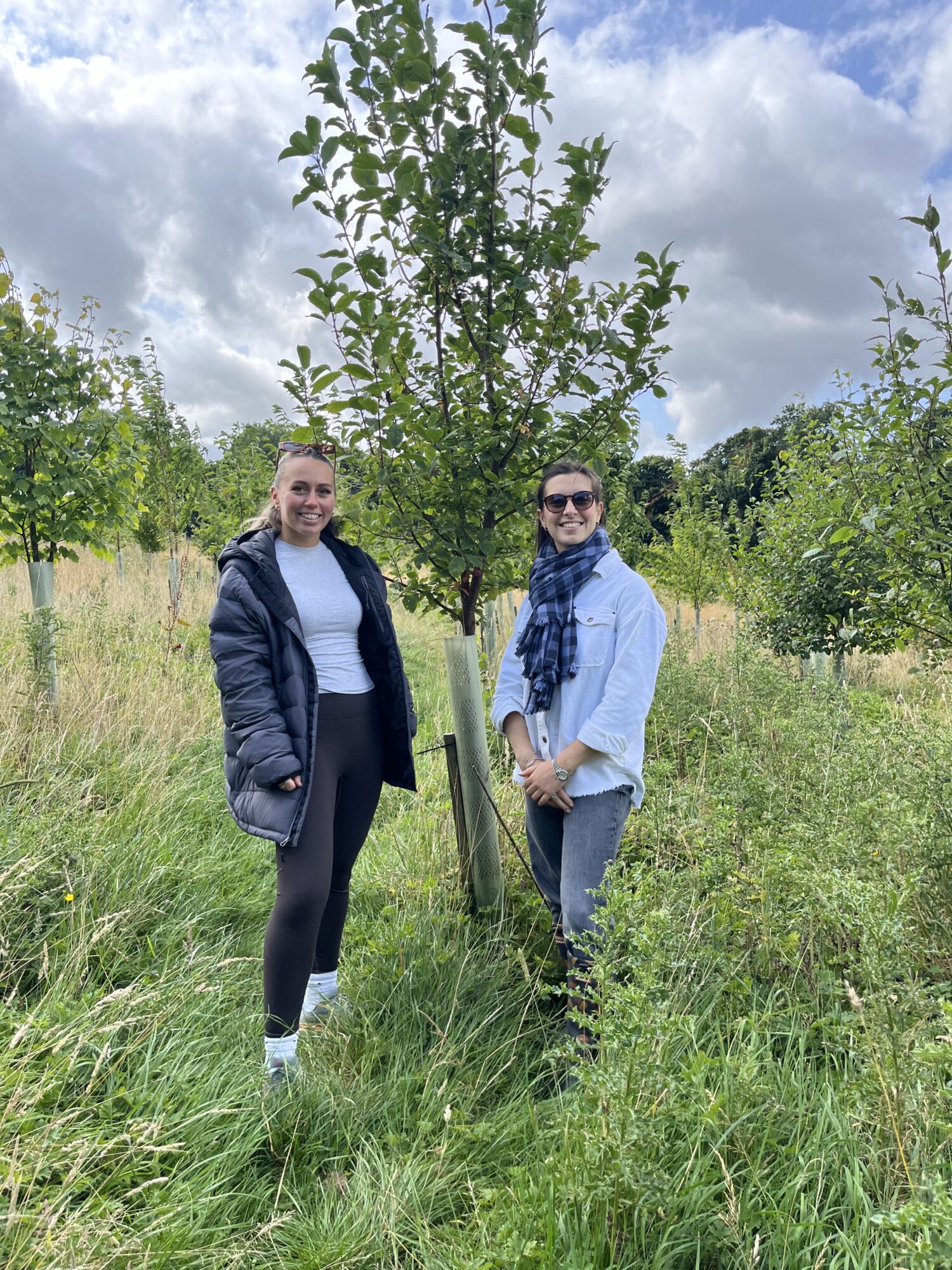 2 members of the Halston B2B team standing in front of trees planted by Make It Wild at Bank Wood