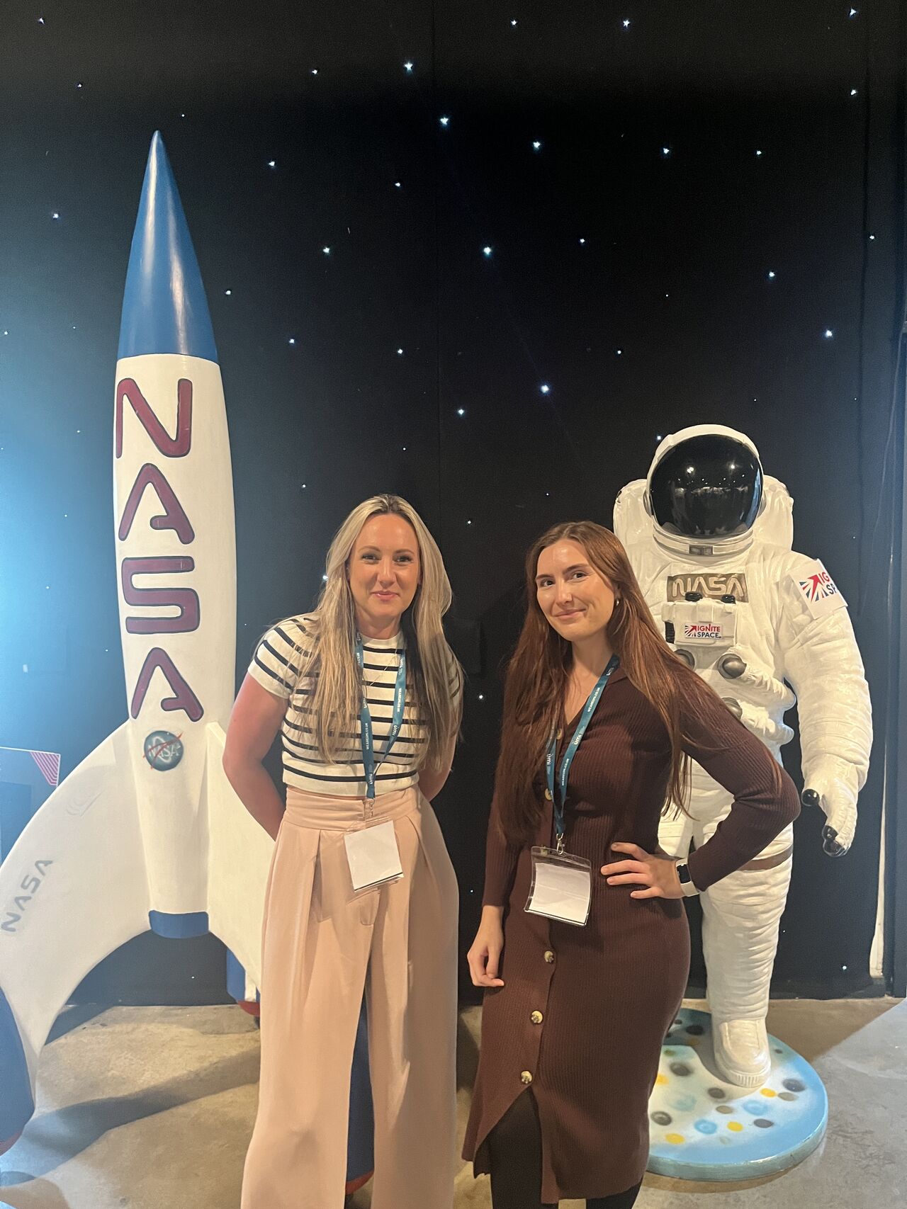 2 members of the Halston B2B team standing in front of a NASA rocket model and a NASA astronaut model